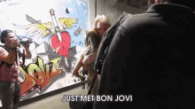 a group of people are standing in front of a graffiti wall that says love