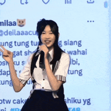 a girl in a school uniform is dancing in front of a screen that says milaa on it