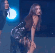 two women are dancing in a dark room with smoke coming out of the ceiling .