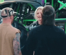a group of people are standing in front of a monster truck talking to each other