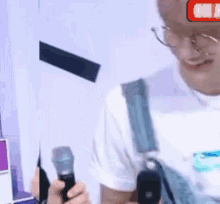 a man with glasses is holding a microphone in his hand .