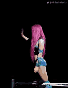 a woman with pink hair and blue shorts is standing in a ring .