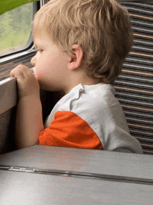 a young boy looks out of a train window