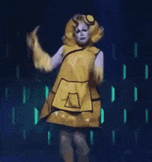 a woman in a yellow dress with the letter a on the pocket
