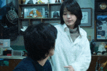 a woman in a white coat talks to a man