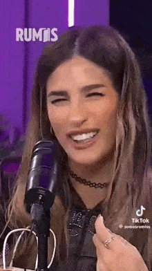 a woman is sitting in front of a microphone with her eyes closed and smiling .