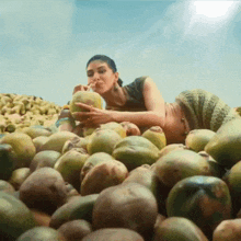 a woman is sitting in a pile of potatoes eating a potato