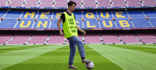a man is kicking a soccer ball in front of a stadium that has the word club on it