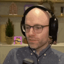 a bald man wearing glasses and headphones with a garfield sticker on his face
