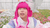 a woman in a pink wig is holding a bouquet of pink flowers