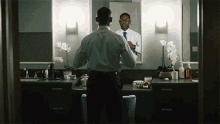 a man is adjusting his tie in front of a mirror
