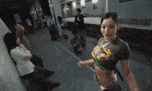 a woman in a crop top is standing in a hallway with people .