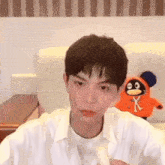 a young man is holding a banana in front of a stuffed animal with a penguin on it .