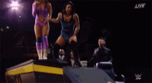 two female wrestlers are shaking hands on a stage .
