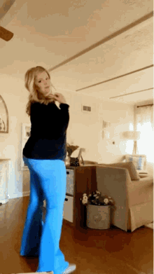 a woman is dancing in a living room with a couch