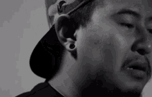 a close up of a man wearing a hat and earrings
