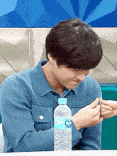 a man in a blue shirt is holding a bottle of water with a blue cap
