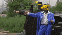 a man in a blue suit points a gun at another man in a black suit