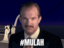 a man with a mustache is standing in front of a ship and the words #mulah are visible
