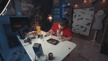 a man in a red shirt is sitting at a table