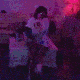 a person sitting on a bed with a microphone in a room with pink lights