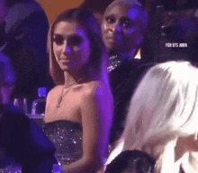 a woman in a strapless dress is sitting in the audience of a concert .