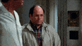 a man wearing glasses stands next to another man in a room