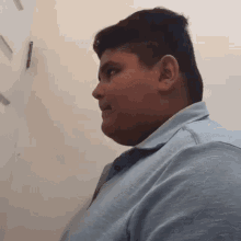 a young man is sitting in front of a white wall and looking at something .