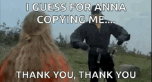 a man and a woman are standing next to each other in a field with a sword .