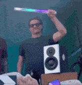 a man is holding a light up stick in front of a speaker with the letter o on it