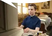 a young boy in a blue shirt is typing on a computer