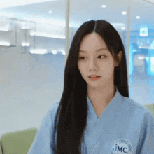 a woman with long black hair is wearing a blue shirt with jmc on it .