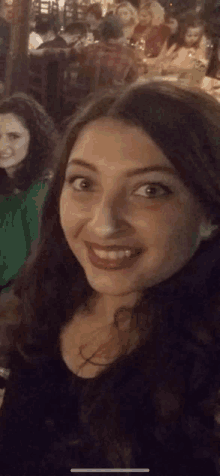 a woman taking a selfie with another woman in the background