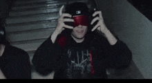 a man wearing red blindfolds and headphones is standing in a dark room .