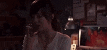 a woman is talking on a cell phone in front of a refrigerator in a kitchen .