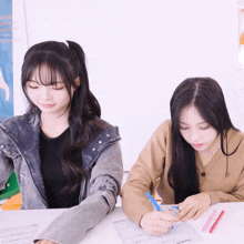 two girls are sitting at a table and one of them is writing on a piece of paper that says ' smart '
