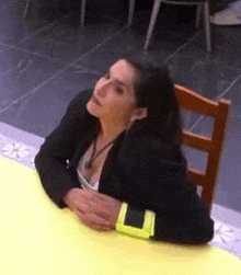 a woman in a black jacket is sitting at a table with her head on a chair .