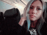 a woman with blue hair is sitting in a plane seat