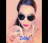 a woman wearing sunglasses and a leopard print shirt is holding a disco ball with the name zelda written on it