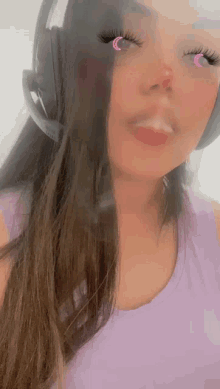 a woman wearing headphones and a purple shirt looks at the camera .