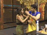 a man wearing a yellow apron with the letter m on it stands next to a woman