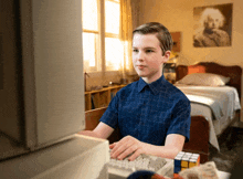a young boy in a blue shirt is typing on a computer