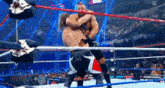 two men are wrestling in a wrestling ring and one of them has arabic writing on his pants