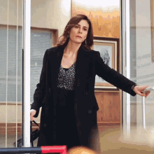 a woman in a black coat opens a door