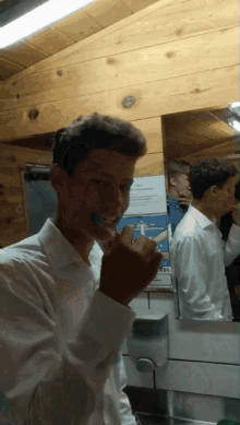 a young man is brushing his teeth in front of a sign that says ' rbs ' on it