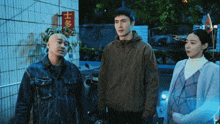three people standing in front of a building with chinese writing