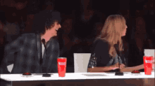 a man and a woman are sitting at a table with coca cola cups on it