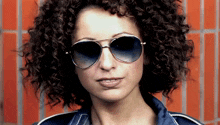 a woman with curly hair is wearing sunglasses