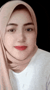 a woman wearing a hijab and a white shirt is smiling