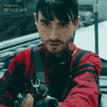 a man wearing glasses and a red shirt is holding a gun with the words made with reface app on the bottom